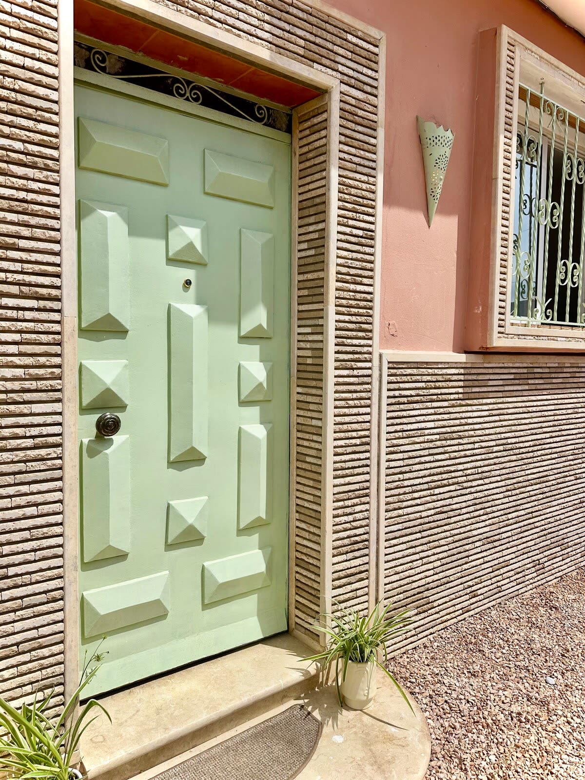 A carved mint-green door set into a textured plaster wall in the village