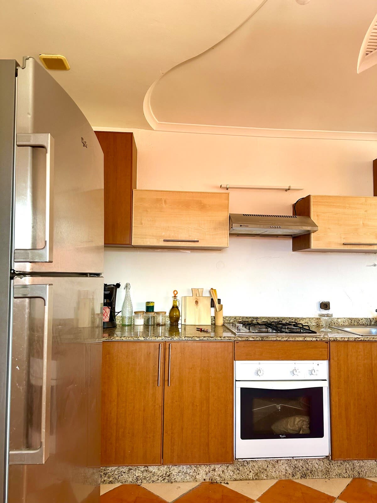 Communal kitchen with wooden cabinets, a gas range and checkered tile floor